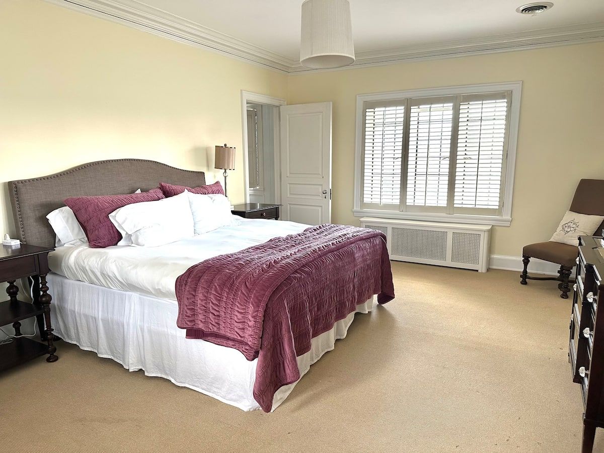 Plum Suite — king bed with mauve bedding and plantation shutters
