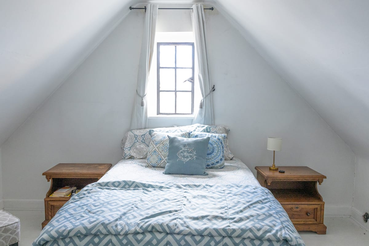 Cozy attic bedroom with peaked ceiling and blue bedding