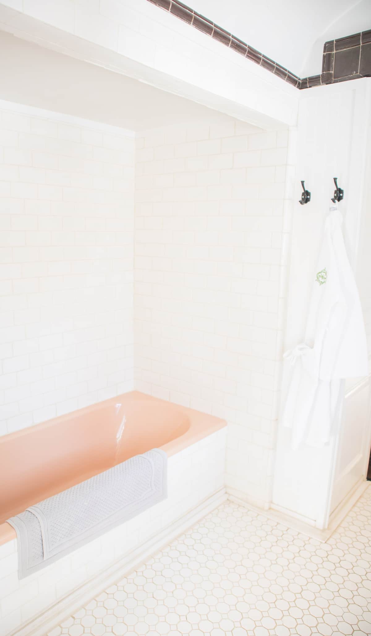 Vintage pink bathtub in white tiled bathroom