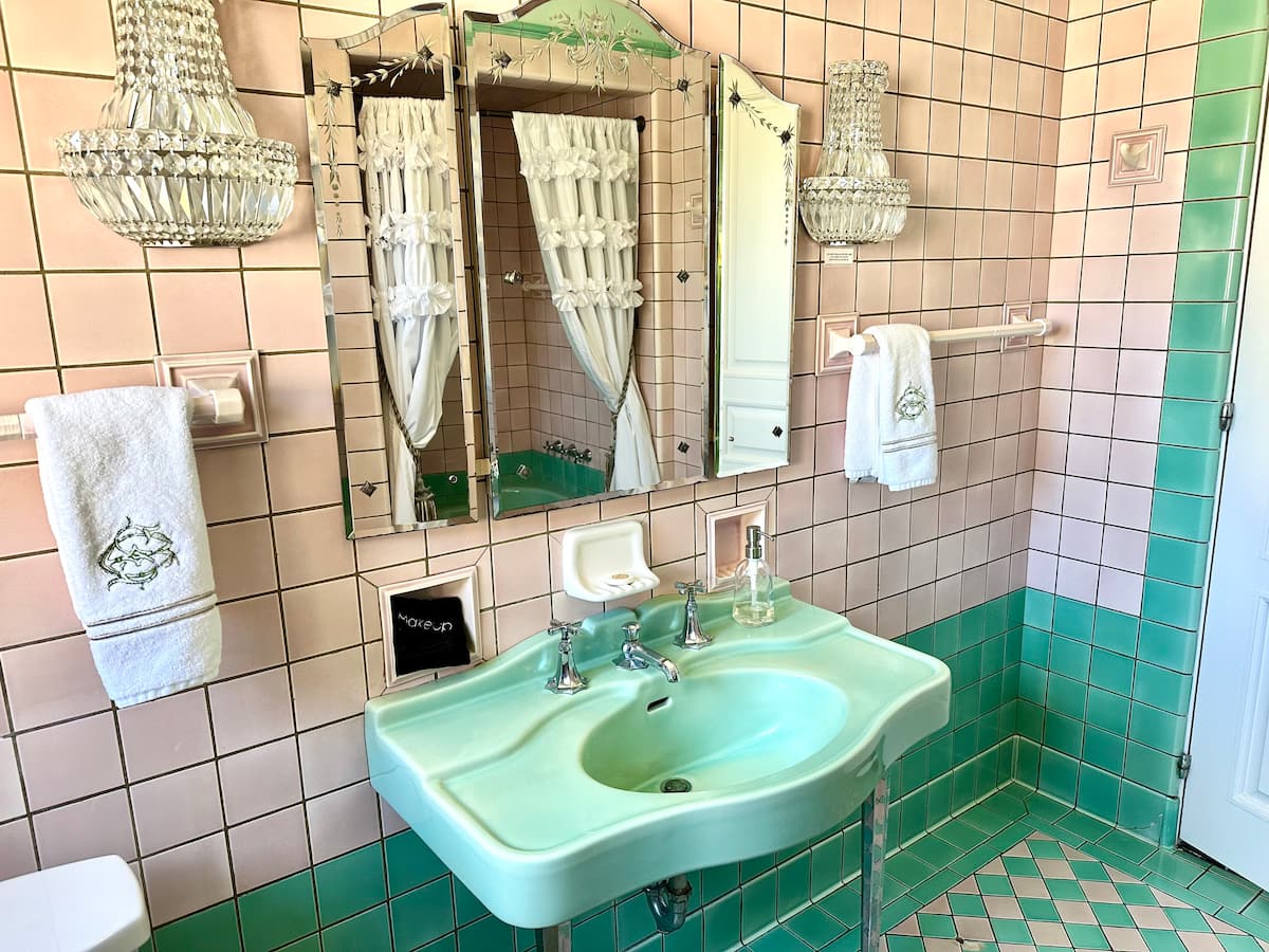 Vintage pink and green tiled bathroom with crystal sconces