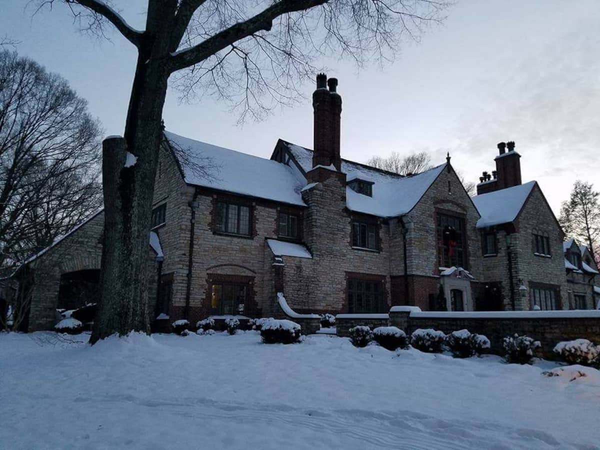 Stone Tudor manor blanketed in winter snow