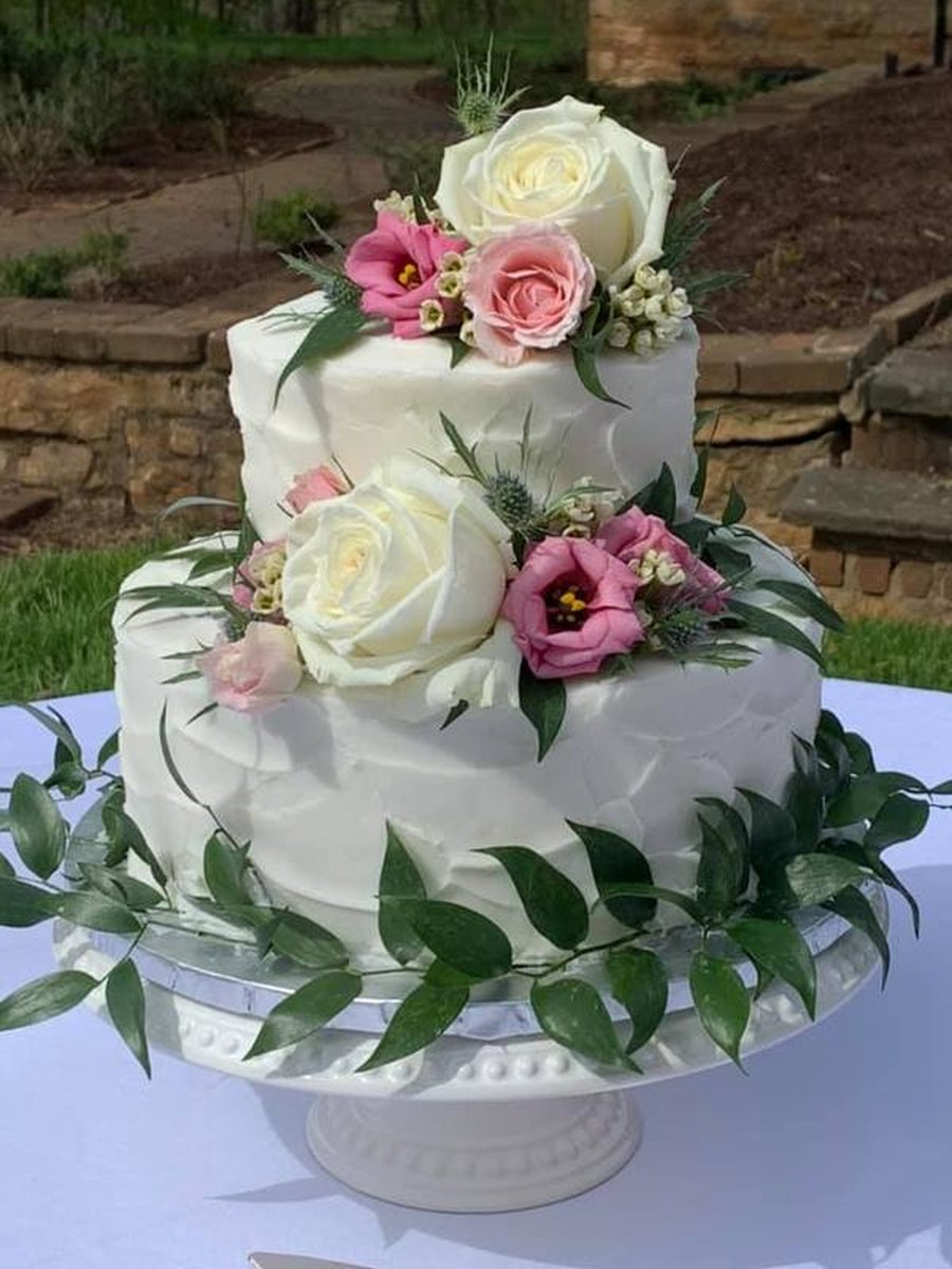 Two-tier white buttercream wedding cake with fresh white and pink roses
