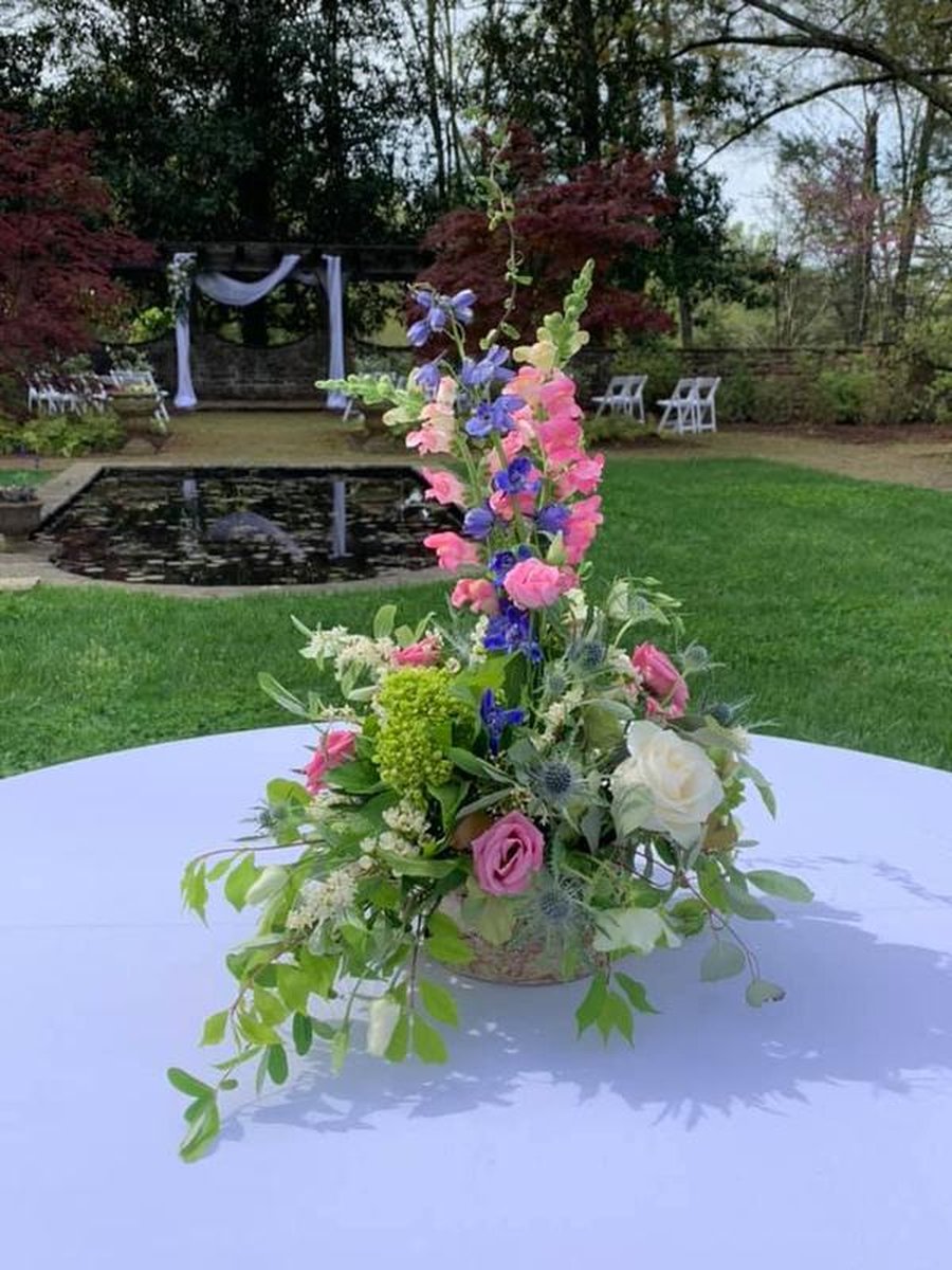 Colorful floral centerpiece with pink snapdragons and blue delphinium on white-clothed table