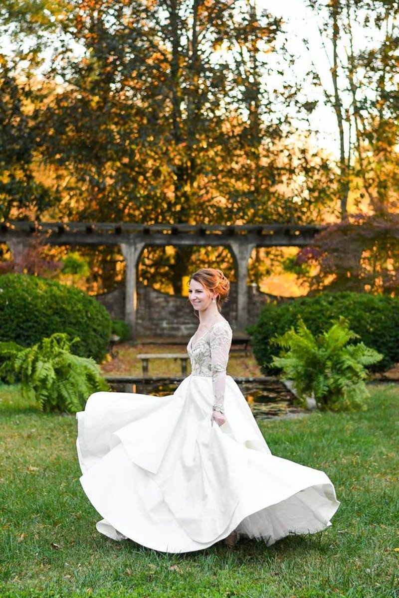 Bride twirling dress in garden with pergola, pond, and ferns during golden hour