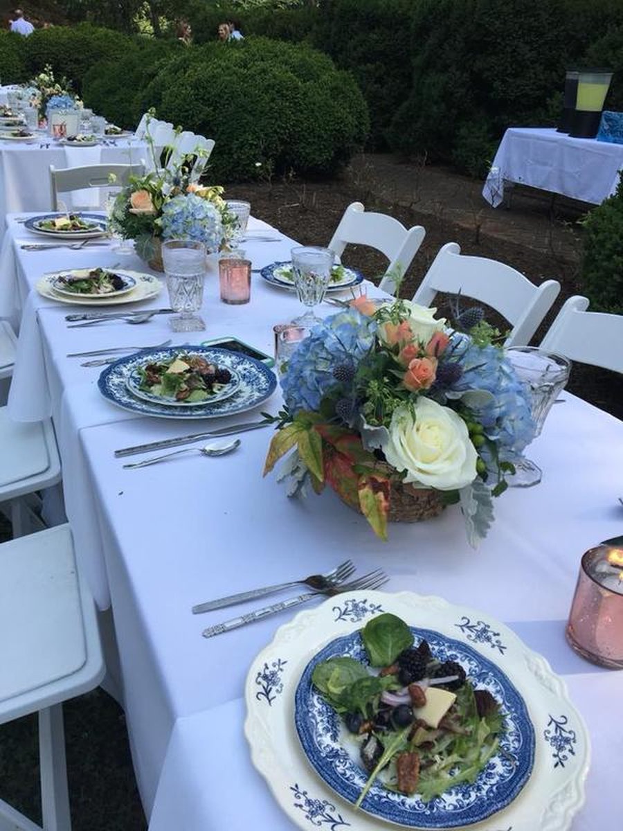Close-up of elegantly set outdoor dining table with blue-and-white china, hydrangea and rose florals