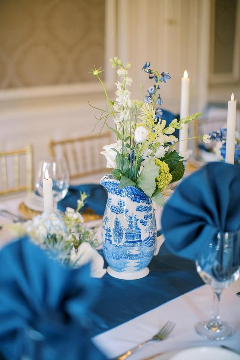 Blue and white chinoiserie pitcher with floral arrangement on elegantly set table
